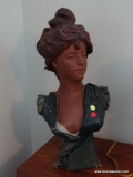 (UPBED 1) VINTAGE CERAMIC BUST OF A WOMAN IN A GREEN OUTFIT. MEASURES 25 IN TALL. ITEM IS SOLD AS IS