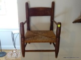 (UPHALL) ANTIQUE CHILDS RUSH BOTTOM ARM CHAIR. MEASURES 14 IN X 12 IN X 19 IN. ITEM IS SOLD AS IS