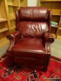 (OFF) BURGUNDY LEATHER UPHOLSTERED RECLINING ARMCHAIR WITH BRASS STUDDING ALONG THE EDGES. MEASURES
