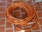 (FRNT PRCH) ORANGE AND WHITE STRIPED GARDEN HOSE. APPROXIMATELY BETWEEN 25 - 50 FT LONG. ITEM IS