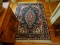 (UPHALL) MACHINE MADE ORIENTAL STYLE RUG IN GREEN IVORY AND RED- 46 IN X 67 IN, ITEM IS SOLD AS IS