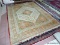 HANDMADE ORIENTAL RUG IN GREEN, ORANGE, AND IVORY. MEASURES APPROXIMATELY 8 FT 11 IN X 11 FT 9 IN.