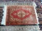 HANDMADE ORIENTAL RUG IN RED, IVORY, AND GREEN. MEASURES APPROXIMATELY 2 FT 3 IN X 3 FT. ITEM IS
