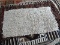 BRAIDED COTTON RUG IN IVORY. MEASURES APPROXIMATELY 2 FT 2 IN X 3 FT 9 IN. ITEM IS SOLD AS IS WHERE