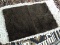MACHINE MADE BATH MAT IN BROWN. MEASURES APPROXIMATELY 1 FT 10 IN X 2 FT. ITEM IS SOLD AS IS WHERE