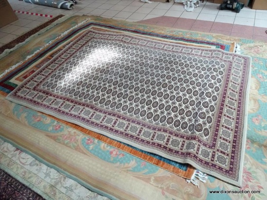 MACHINE MADE BOKHARA STYLE RUG IN IVORY, RED, AND BEIGE. MEASURES APPROXIMATELY 5 FT 3 IN X 7 FT 7