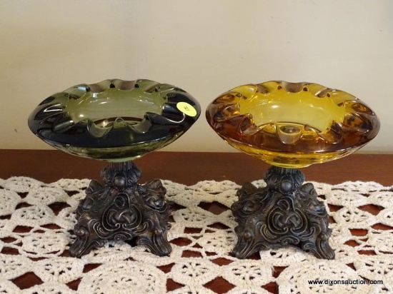 (DR) PAIR OF ORNATE GLASS AND METAL ASHTRAYS. ONE IS AMBER GLASS AND THE OTHER IS BLUE/GREEN. EACH