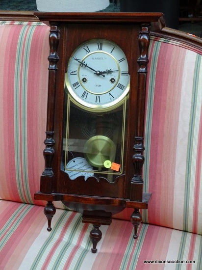 (R1) KASSEL WALL HANGING CLOCK WITH MAHOGANY CASE AS WELL AS BRASS AND WOOD PENDULUM. MEASURES 11 IN