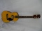 (BAY 7) HARMONY ACOUSTIC GUITAR WITH HARDSHELL CASE. NEEDS 2 TUNING KEYS, STRINGS, AND A NUT. ITEM
