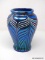 A metallic iridescent blue vase having a wide mouth with a slightly rolled lip above wide shoulders