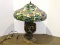 Stained And Slagged Glass Floral Pattern Lamp With Bronze Toned And Cherub Themed Base. Primary