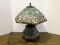 Stained And Slagged Glass Floral Pattern Lamp With 6 Legged Bronze Tone Base. Primary Colors Include