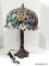 Slagged And Stained Glass Lamp With Bronze Toned Twist Tree Style Base. Primary Colors Include Pink,