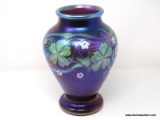 Purplish brown iridized glass with surface decoration of green and white floral motif having
