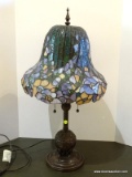 Double Light Floral Pattern Slagged And Stained Glass Lamp With Bronze Toned Bird Themed Base.