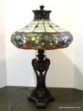 Slagged And Stained Glass Lamp With Bronze Toned Urn Style Base. Primary Colors Include Cream,