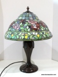 Slagged Glass Lamp With Bronze Toned Urn Style Base. Primary Colors Include Green, Red, Blue, And
