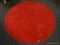 (R2) ROUND RED AREA RUG. MEASURES APPROXIMATELY 4 FT IN DIA. ITEM IS SOLD AS IS WHERE IS WITH NO