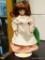 (R3) PORCELAIN DOLL WITH STAND. MEASURES 8.5 IN TALL. ITEM IS SOLD AS IS WHERE IS WITH NO GUARANTEE