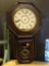 (R3) ANTIQUE REGULATOR STYLE CLOCK WITH HAND PAINTED DOOR AND PORCELAIN FACE. HANDS NEED TO BE