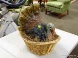 (R2) CERAMIC TURKEY ON BASKET DECORATION. MEASURES APPROXIMATELY 14 IN X 10 IN X 15 IN. ITEM IS SOLD