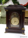 (R2) BOMBAY MANTLE CLOCK WITH MAHOGANY CASE AND BRASS FEET. MEASURES 9 IN X 4.5 IN X 12.5 IN. ITEM