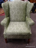 (R3) SIGMONS GREEN UPHOLSTERED WING BACK CHAIR WITH MAHOGANY LEGS. IS 1 OF A PAIR. MEASURES 34 IN X