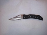 FROST CUTLERY FOLDING KNIFE WITH BLACK PLASTIC HANDLE AND A SERRATED BLADE. APPROXIMATELY 6 1/2