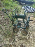 (S3HILL) GREEN METAL HOSE REEL PULL BEHIND CART. HAS LOWER BASKET STORAGE AREA. SOME RUSTING ALL