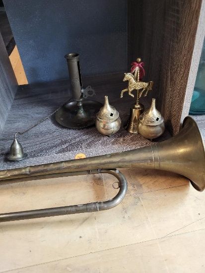 BRASS SHELF LOT. LOT INCLUDES LIDDED BRASS POTS, BUGLE, CANDLEHOLDER AND BELL. IS SOLD AS IS WHERE