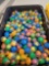 BLACK AND YELLOW TOTE LOT OF ASSORTED GUMBALL MACHINE CAPSULES. MOST APPEAR TO BE TONGUE TUGGERS.