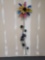 TALL METAL MULTI-COLORED SUNFLOWER YARD ORNAMENT WITH A BUTTERFLY AMING THE LEAVES ON THE STALK. THE