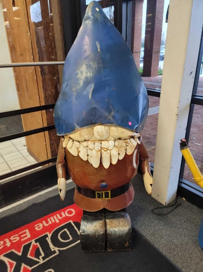 BENCHMADE METAL GNOME YARD ORNAMENT. HE IS WEARING A BLUE HAT AND A RED OUTFIT. MEASURES APPROX 25"