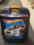 BLACK PLASTIC HOT WHEELS CARRYING CASE FILLED WITH ASSORTED TOY CARS. CASE HAS PULL UP HANDLE AND