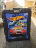 BLACK PLASTIC HOT WHEELS CARRYING CASE FILLED WITH ASSORTED TOY CARS. CASE HAS PULL UP HANDLE AND