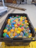 BLACK AND YELLOW TOTE LOT OF ASSORTED GUMBALL MACHINE CAPSULES. MOST APPEAR TO BE ANIMALS, YOYOS,