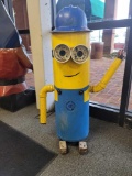 BENCHMADE MINIONS YARD ORNAMENT MADE FROM AN OLD TANK. PAINTED YELLOW WITH BLUE OVERALLS. HAS A BLUE