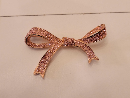 (DR) MARKED "KJL" DESIGNER ROSE GOLD TONED BOW BROOCH ACCENTED WITH SM. PINK CRYSTALS. IT MEASURES