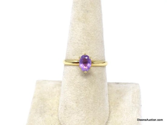 GOLD TONE ENGAGEMENT RING WITH AN APPROX. 1 CT. OVAL CUT PRONG SET SIMULATED AMETHYST STONE.