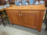 WOODCRAFT INDUSTRIES PINE TWO DOOR STORAGE CABINET. BOTH DOORS HAVE A WHITE ENAMEL KNOB. IT OPENS UP