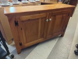 WOODCRAFT INDUSTRIES PINE TWO DOOR STORAGE CABINET. BOTH DOORS HAVE A WHITE ENAMEL KNOB. IT OPENS UP