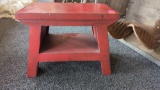 EARLY STYLE FIRE RED WOODEN STOOL WITH A SMALL UNDER SHELF MEASURES APPROXIMATELY 12 IN X 7 IN X 9