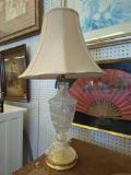 GLASS URN STYLE TABLE LAMP ON BRASS BASE WITH A BRASS HARP, CHAMPAGNE COLORED SHADE & BRASS FINIAL.