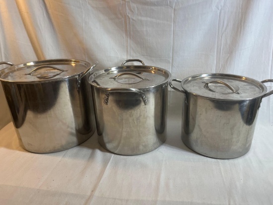 Three large stainless steel stock pots with lids. Middle one is 10" tall.