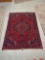 HAND MADE ANTIQUE AREA RUG. FLORAL ACCENTS, RED, AND DARK BLUE. 44 1/2