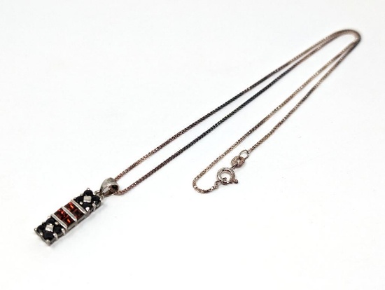 .925 STERLING SILVER RECTANGULAR PENDANT WITH SQUARE CUT GARNETS AND ROUND CUT SAPPHIRES. DISPLAYED