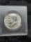 1964 Kennedy Half Dollar - hard plastic container, ungraded