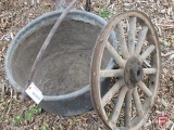 Large metal pot with handle, possibly copper, small holes in bottom; and old wheel