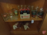 Contents of 2 shelves: Coca Cola glasses and plastic cups, 1899 replica Coca Cola six pack,