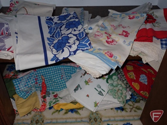 Table coverings, aprons. Contents of bottom shelf and on floor of closet.
